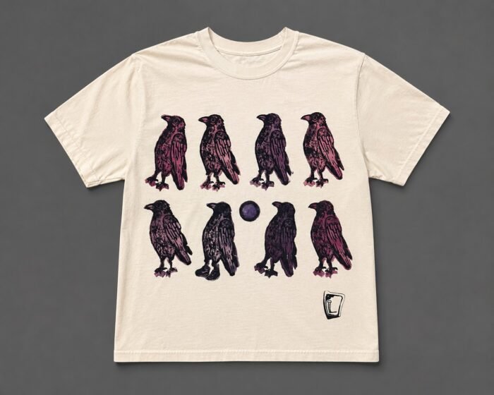 Cream tee hand printed with eight ravens in purple and pink around a dark orb