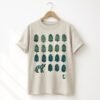 Sand-colored tee hand printed with green and teal pinecones and a coyote